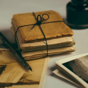 decorative image of old papers wrapped in a bundle with twine, with old photos, fountain pen and inkwell